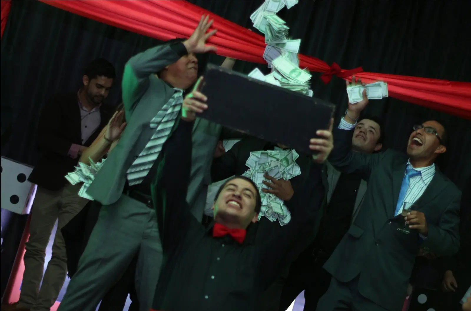 Invitados celebrando con billetes de juego y una caja durante una producción de Casino