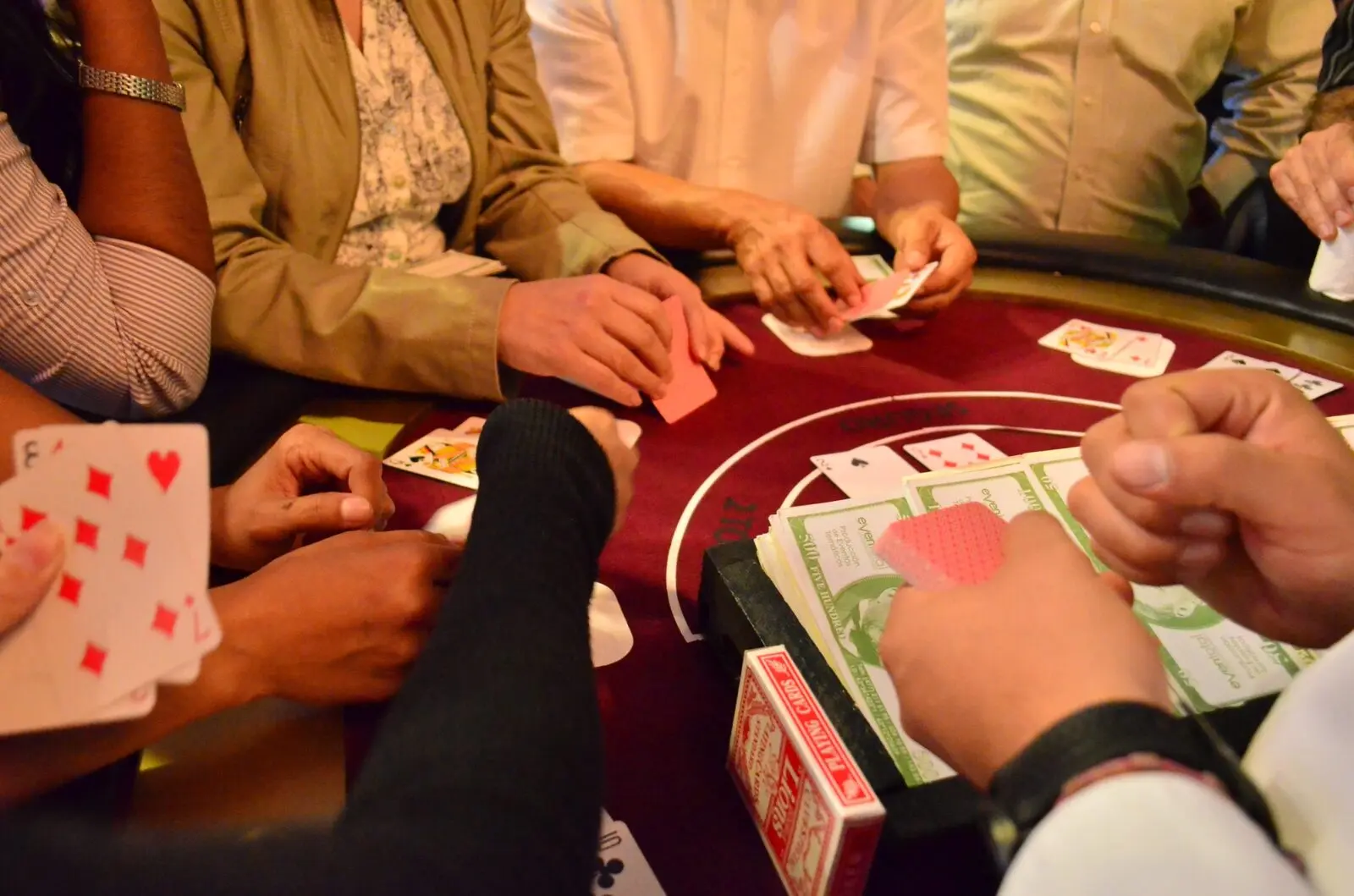 Detalle de manos, cartas y billetes en una mesa de Casino producida por Eventotal