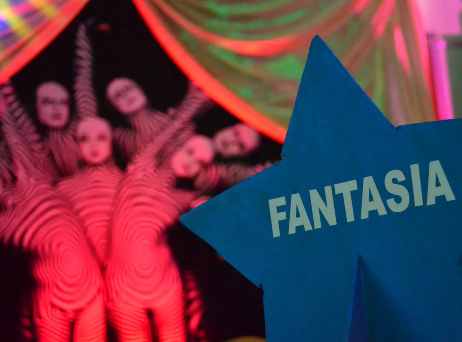 Personajes de una producción temática de Circo de Eventotal junto a un letrero de Fantasía