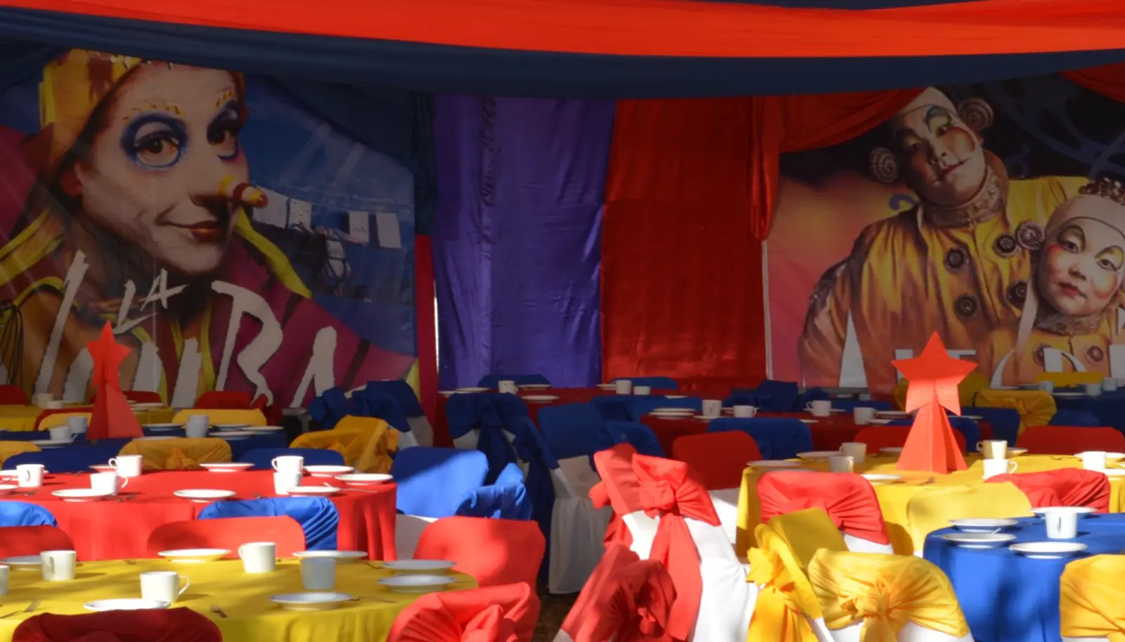 Mesas decoradas con colores y escenografía de una producción temática de Circo