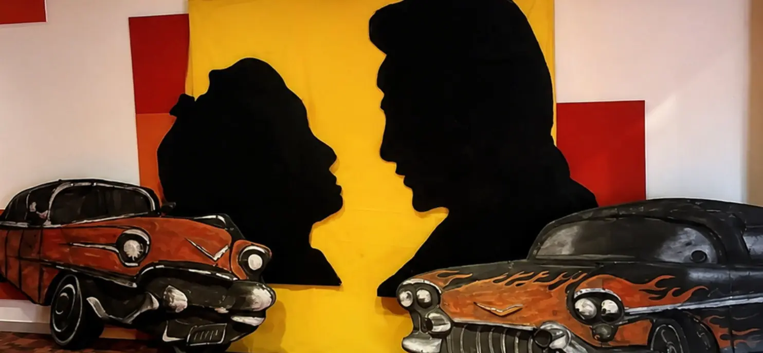 Escenografía temática de los años 50 con siluetas y automóviles clásicos