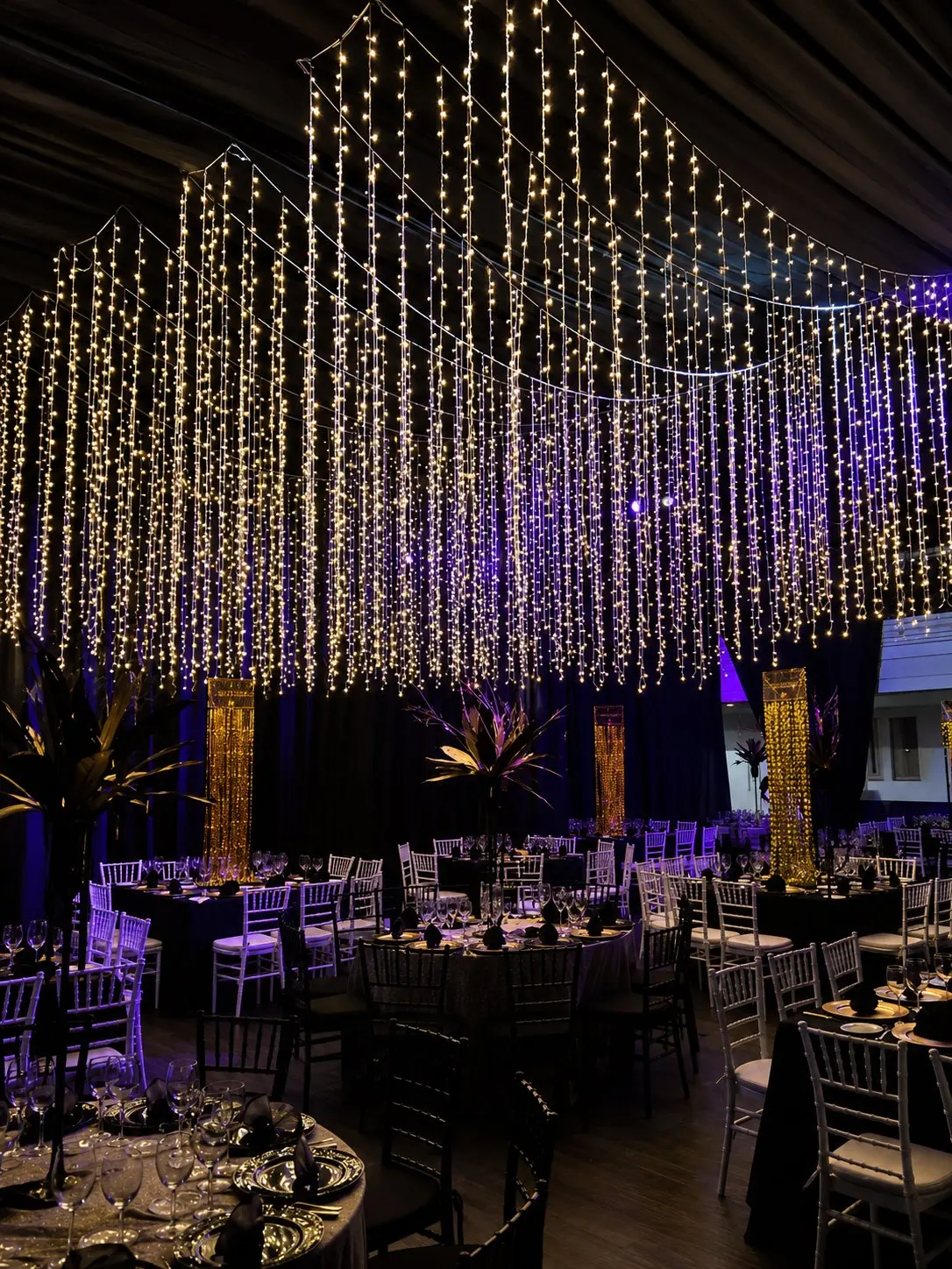 Salón corporativo con cortinas de luces, mesas formales y ambientación elegante