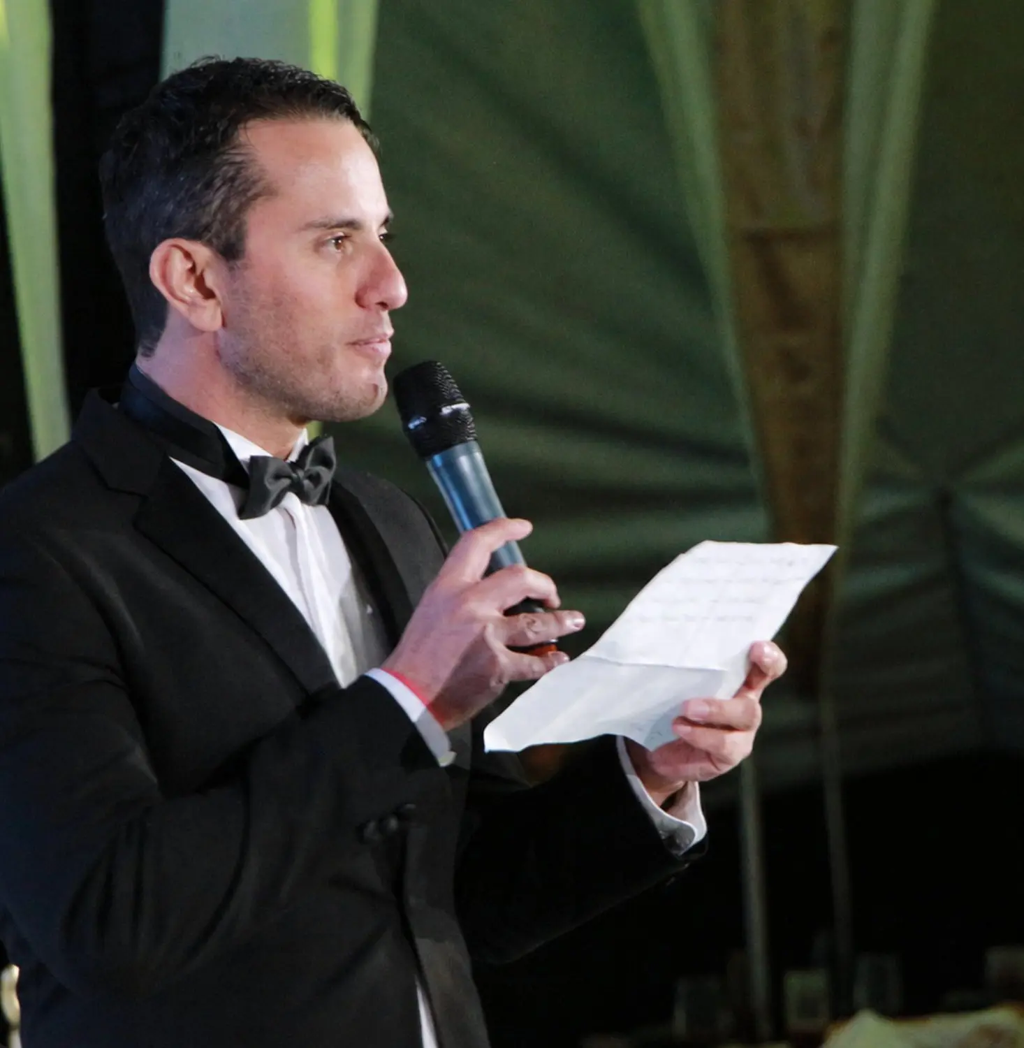 Maestro de ceremonias con esmoquin leyendo el programa de un evento protocolario
