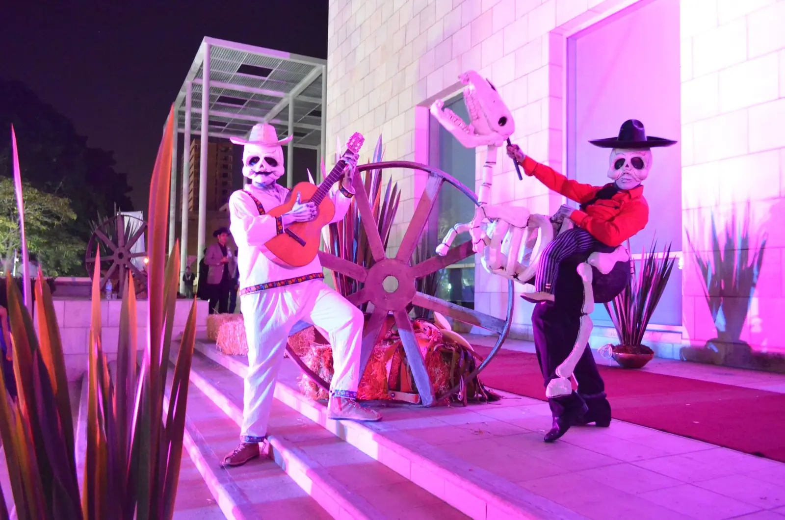 Personajes de calavera con guitarra y caballo escenográfico en una producción mexicana