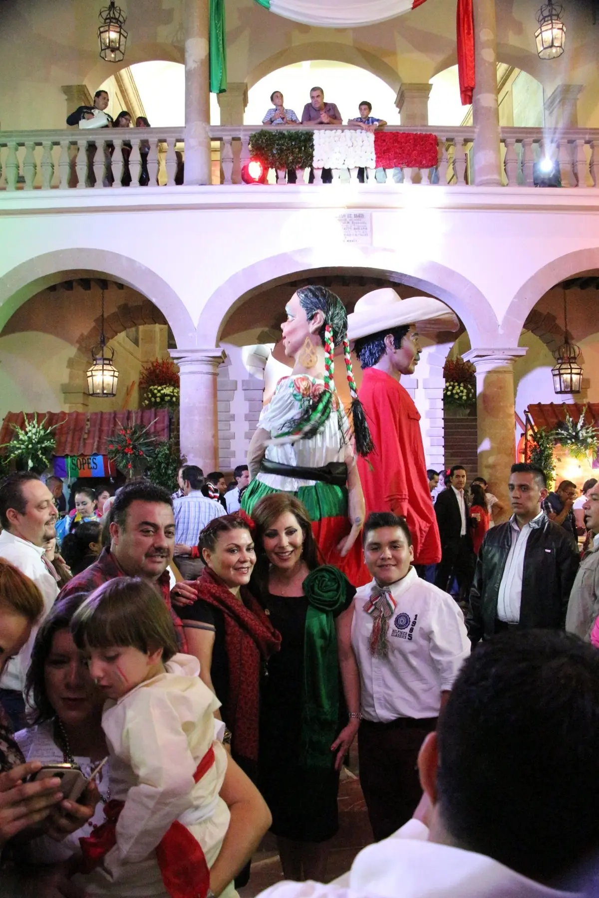 Invitados junto a figuras mexicanas gigantes dentro de un patio decorado