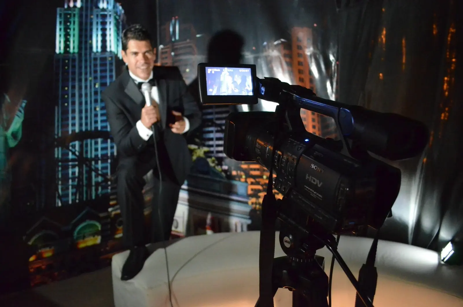Cámara profesional grabando a un conductor frente a una escenografía de ciudad