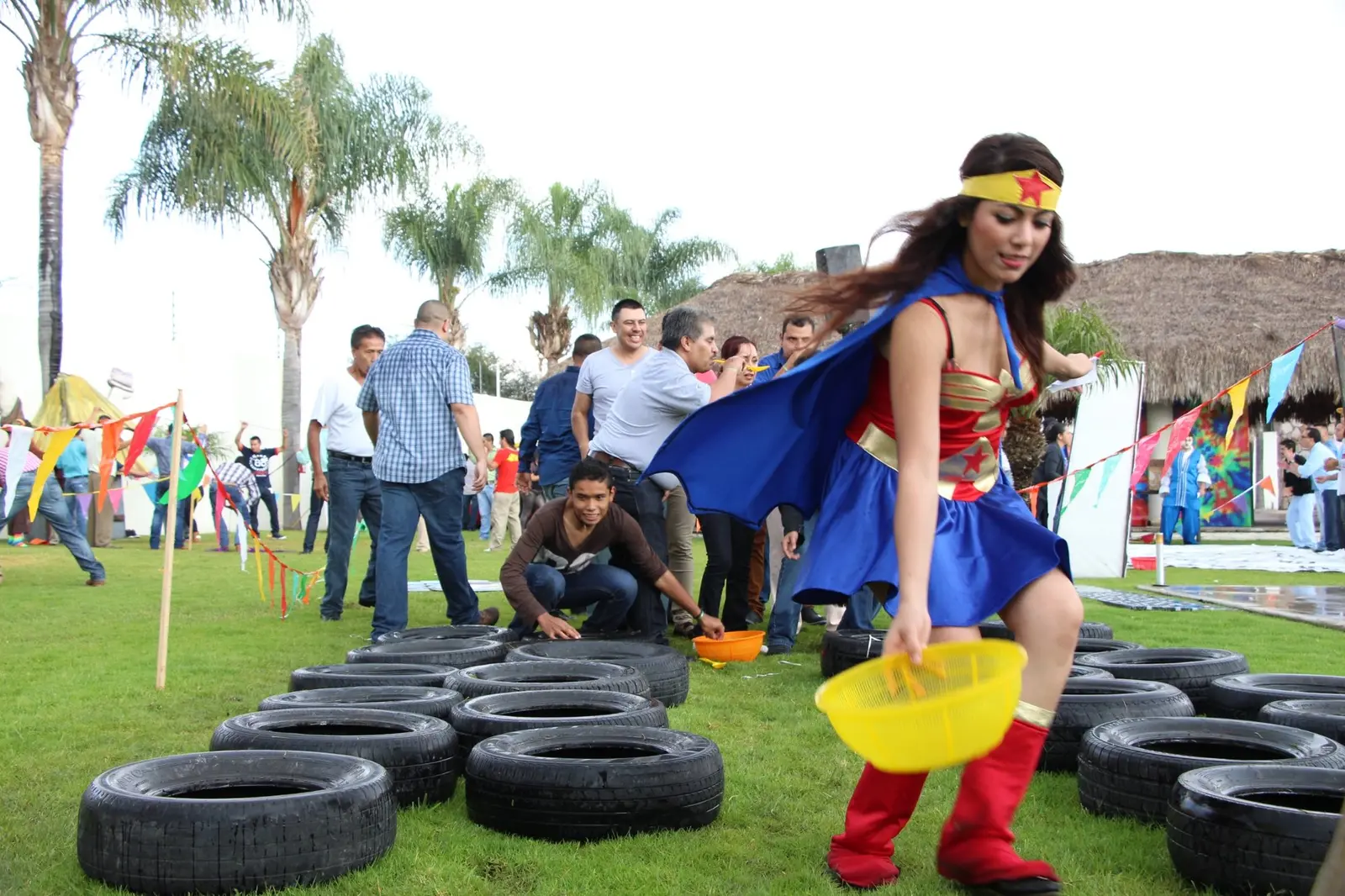 Participante caracterizada como superheroína avanza por un circuito de llantas al aire libre