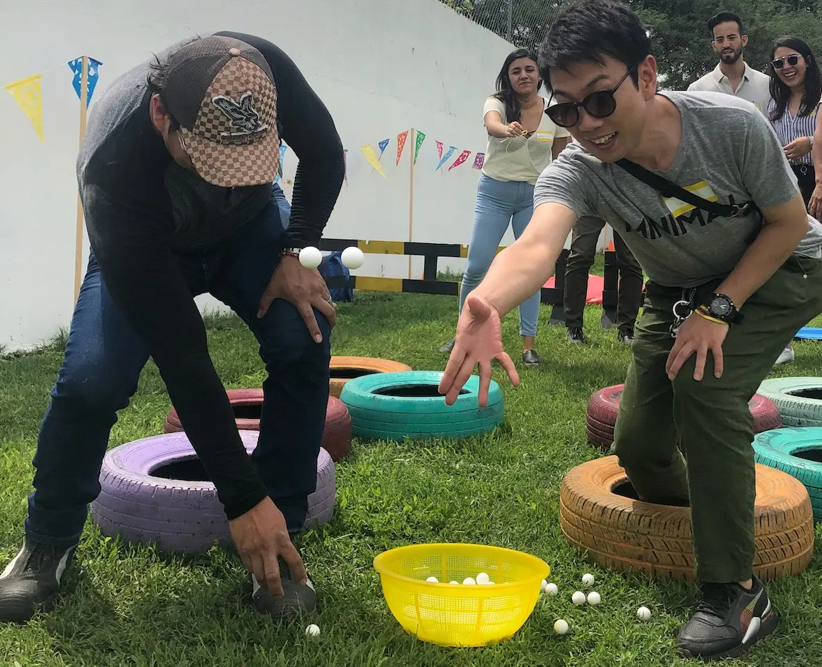 Participantes compitiendo en un circuito de llantas con pelotas durante un Team Building