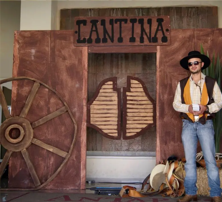 Fachada de cantina del viejo oeste con rueda de carreta y personaje caracterizado