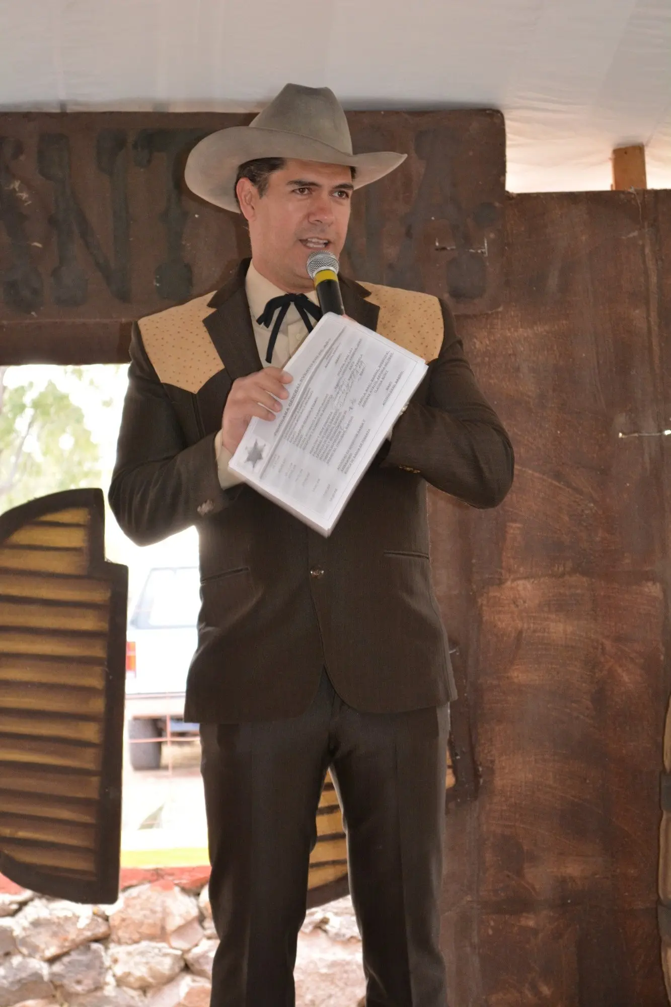 Conductor caracterizado como vaquero hablando frente a una escenografía Western